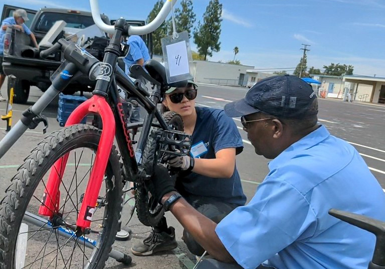 A man and a woman work on a bicycle outside.
