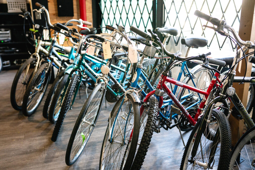 Row of bikes next to a window - mostly blue or red.