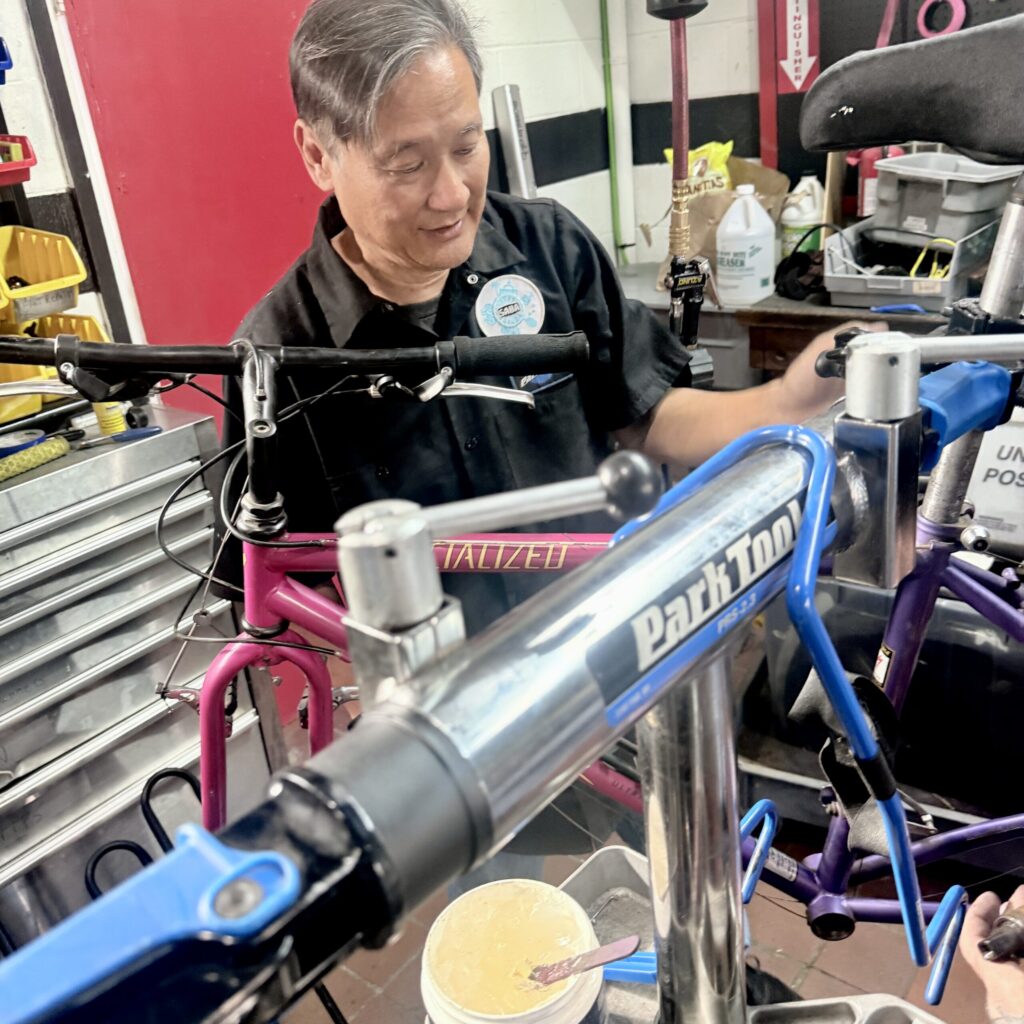 An older Asian man works on a bicycle.